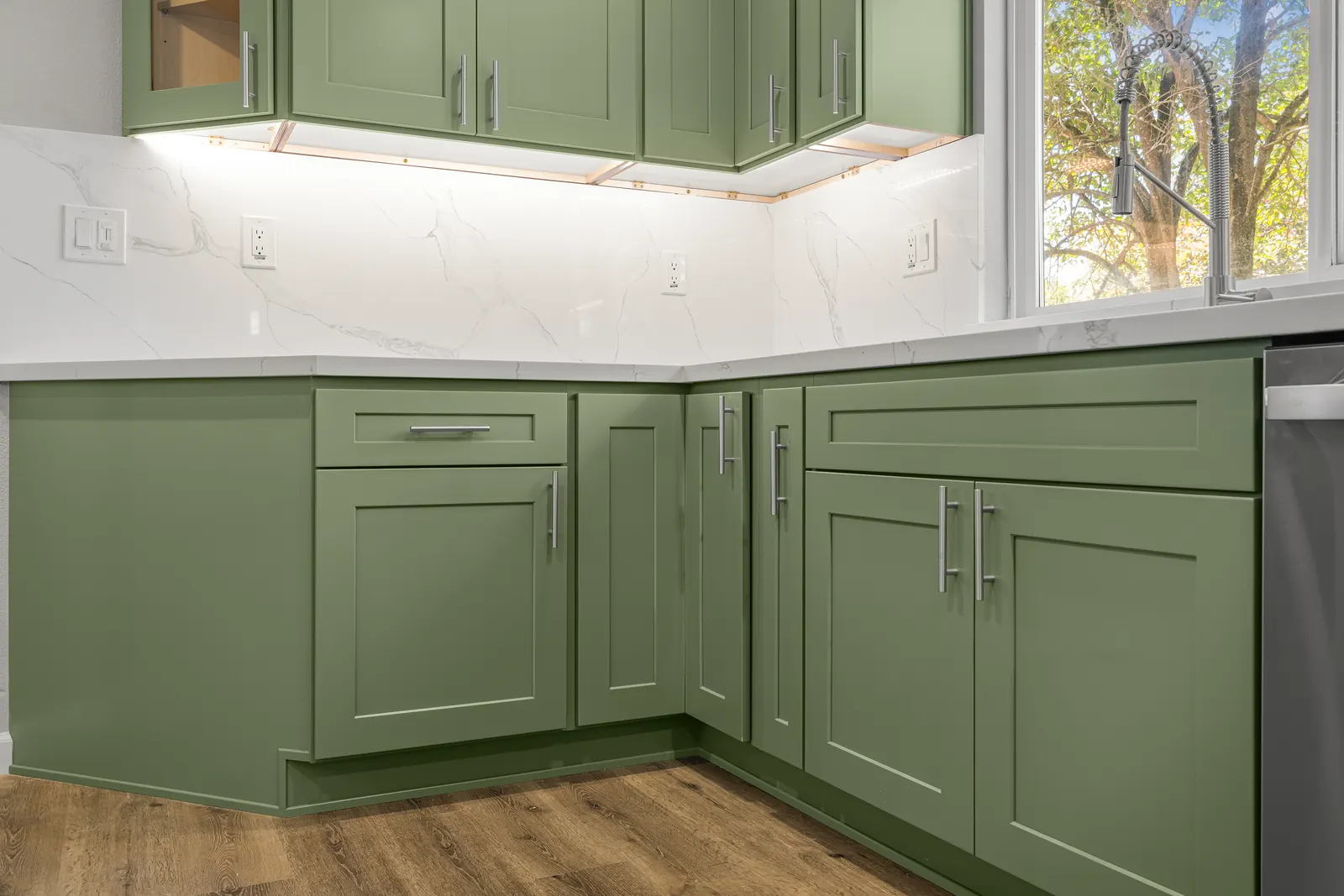 Green lower cabinets with quartz countertop and under-cabinet lighting